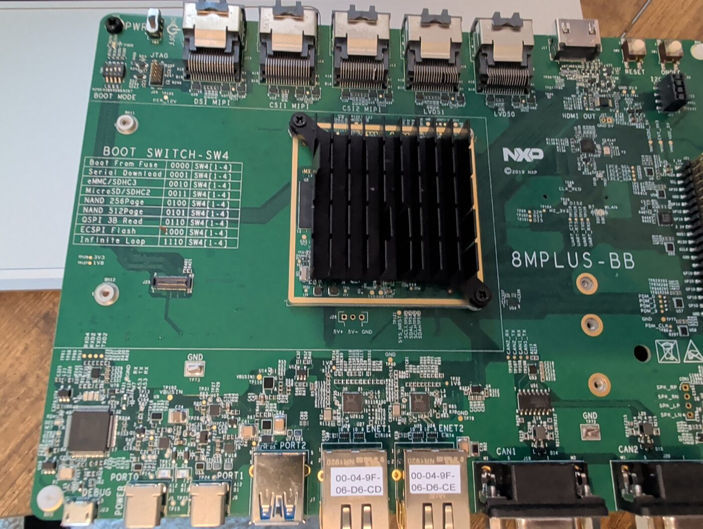 NXP i.MX 8M Plus EVK base board, 8MPLUS-BB, with the system-on-module fitted under a heatsink, showing the BOOT SWITCH SW4 table, two ethernet ports, two CAN ports and MIPI DSI, CSI and LVDS connectors